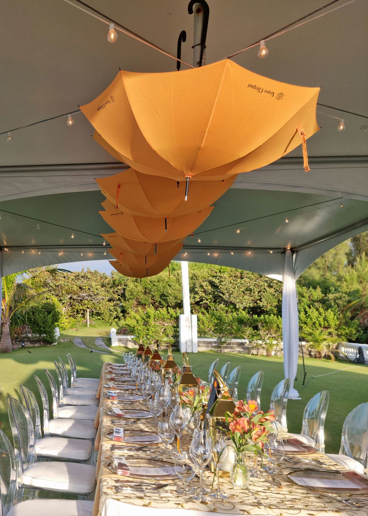 Event setup with white folding chairs arranged on green grass with trees and hills in background