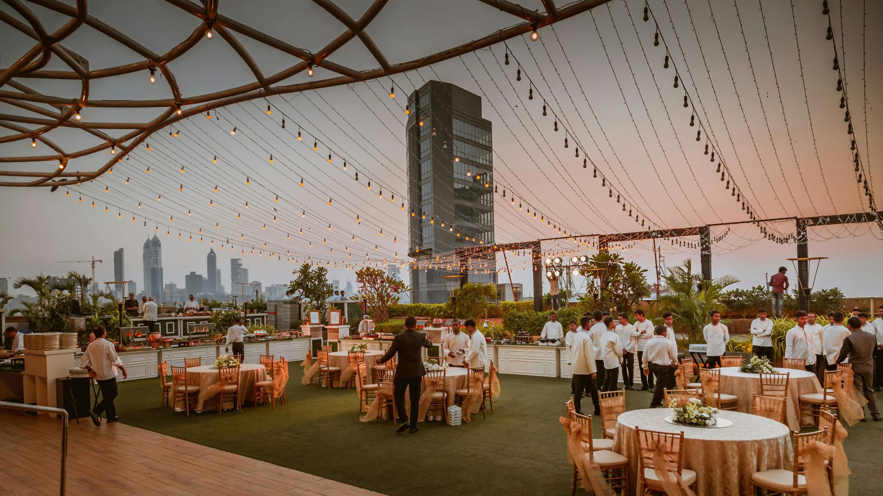 Event setup with white folding chairs arranged on green grass with trees and hills in background